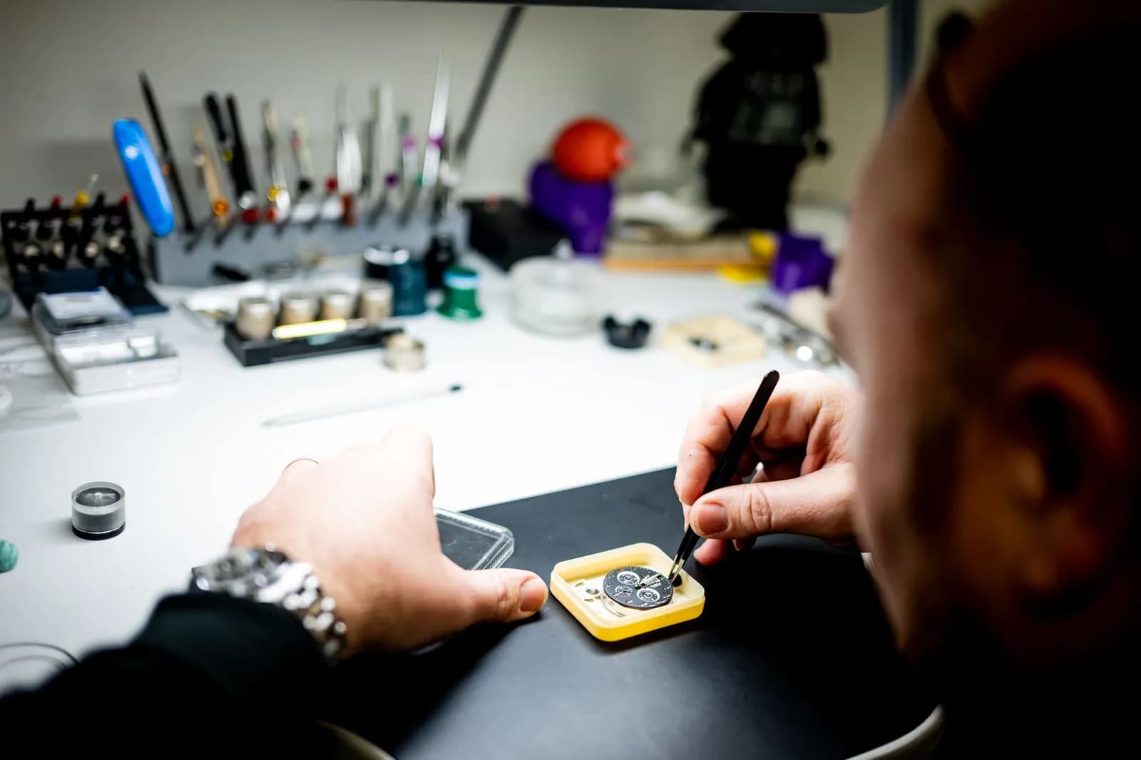 Horloger réparant une montre à son établi avec des outils de précision