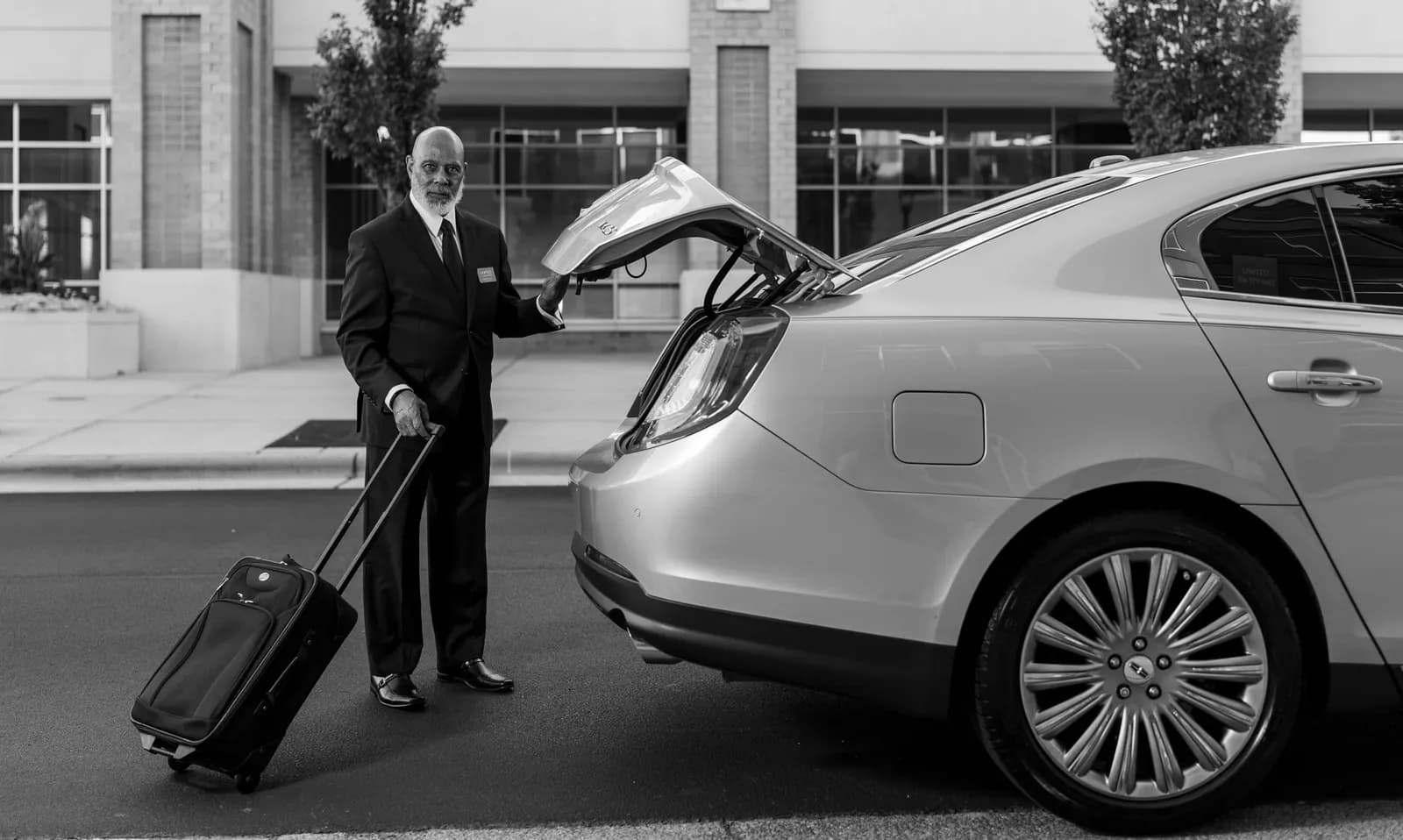 Chauffeur en costume chargeant une valise dans une berline